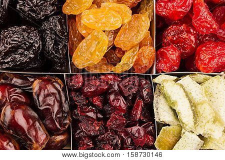 Assortment of dried fruits closeup background in square cells. Decorative pattern of dry exotic fruit. Top view.