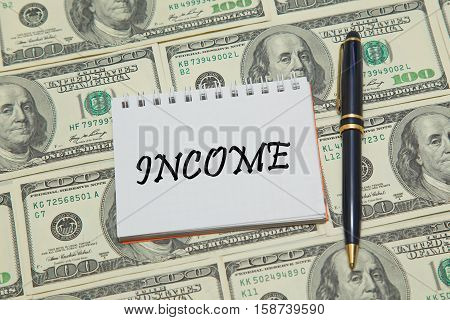 Notebook page with text INCOME on dollar background