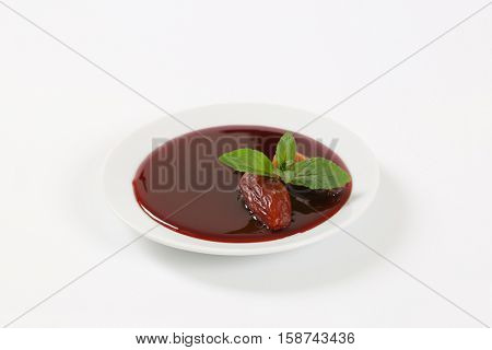 plate of date syrup with dates on white background