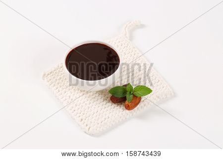 bowl of date syrup with dates on white table mat