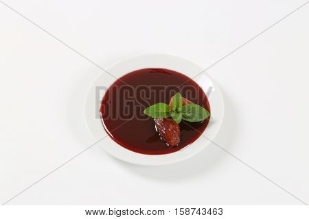 plate of date syrup with dates on white background
