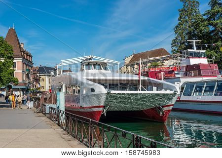 Annecy France - May 25 2016: Tourist excursion boats are moored at the pier seen during the spring sunny day in Annecy Haute Savoie French Alps France. Annecy Lake is one of most popular French resorts. For example a boat trip to discover luxurious landsc
