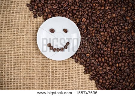 White coffeeplate with smiley coffeebeans on gunny background