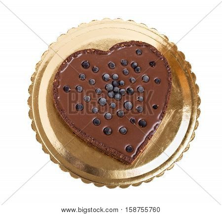 Delicious chocolate cake with blueberries in form of heart on golden cardboard stand. Isolated on a white background.