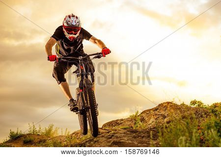 Professional Cyclist Riding the Bike Down Rocky Hill at Sunset. Extreme Sport Concept. Space for Text.
