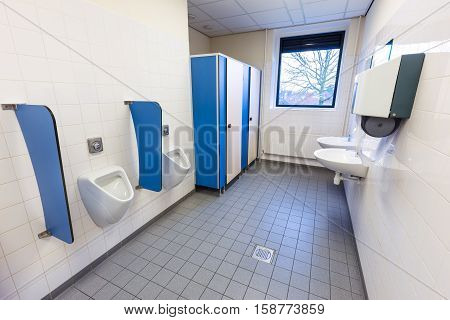 Toilet room for men with urinals sinks and towel dispenser on high school