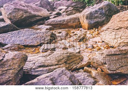 Rocky shore texture background. Stones Rocks Sand on sunset time. Selective focus