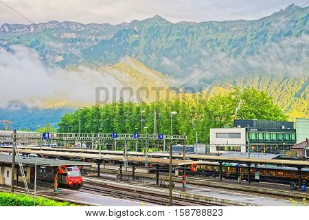 Interlaken Switzerland - August 24 2013: Railway station with train in Interlaken and Swiss Alps in Interlaken Oberhasli district of Bern Canton in Switzerland
