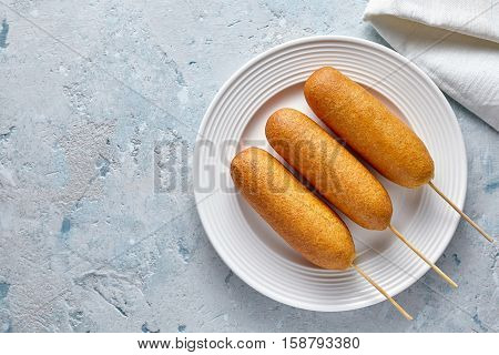 Corn dog traditional American corndog food deep fried hotdog meat sausage snack treat coated in a thick layer of cornmeal batter on stick unhealthy eating on rustic table.