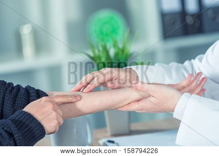 Female patient at orthopedic medical exam in doctor's hospital office traumatology and medical consultation for hand wrist injury