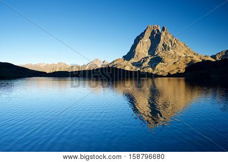 Midi Dossau Peak reflected in Gentau lake. Ossau Valley, Pyrenees National Park, Pyrenees, France.