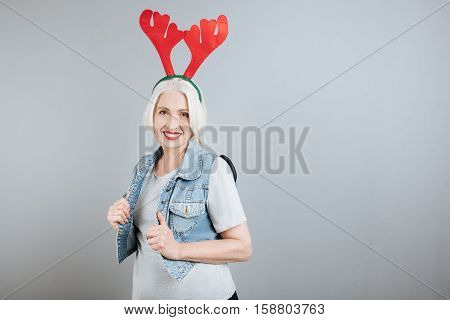 Reddy for Christmas. Beautiful pleasant senior woman smiling and standing against isolated gray background.