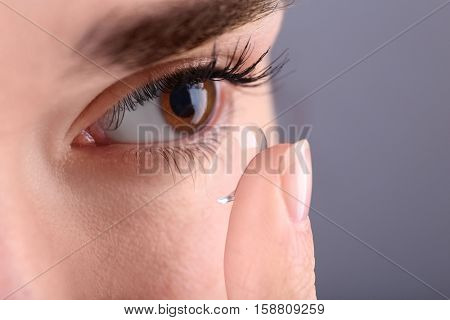 Woman putting contact lens in her eye, closeup