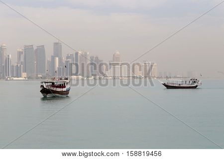 A misty morning in Doha, Qatar, in  2016, fades the towers of the Dafna business district behind the moored dhows.
