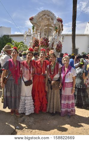 Huelva, Spain - June 5, 2014: Women with typical dresses in way of pilgrimage El Rocio in front of the the pennant of the religious brotherhood in the countryside of Huelva Spain