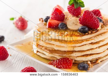 Pancakes with berries and maple syrup, close-up.