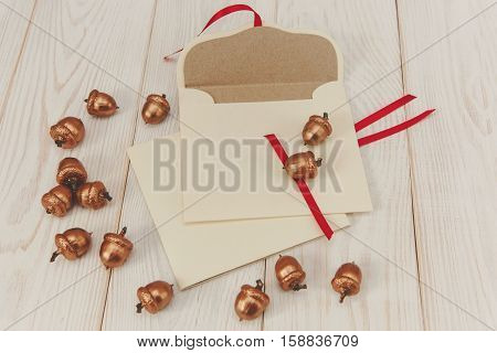 Christmas background.Envelopes with golden acorns.White wooden table.Empty space