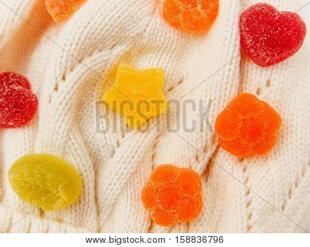 Background from jelly colorful candies in the knitted white hat.Top view