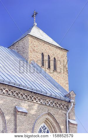 Yellow brick church tower with cross in Vepriai Lithuania