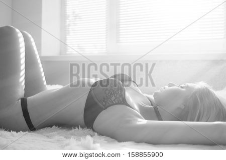 sensual girl in lingerie lying on fur in sun light, monochrome