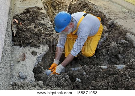 Plumber At Construction Site Repair Sewerage Tube