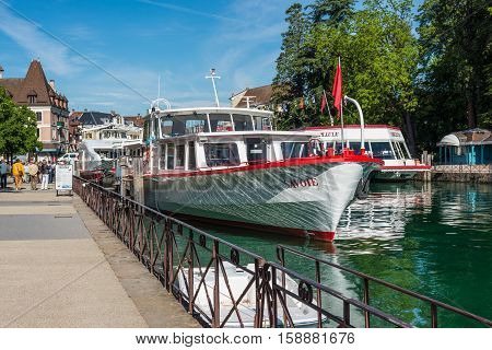 Annecy France - May 25 2016: Tourist excursion boats are moored at the pier seen during the spring sunny day in Annecy Haute Savoie French Alps France. Annecy Lake is one of most popular French resorts. For example a boat trip to discover luxurious landsc