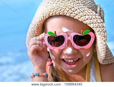 Happy child in glasses with sunscreen on the face