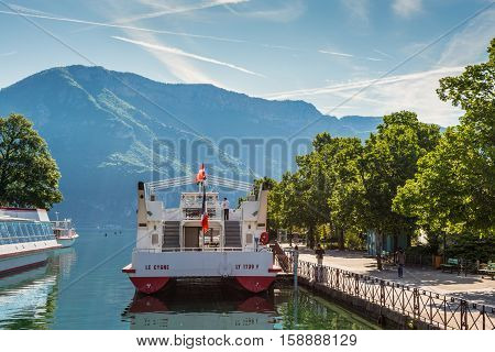 Annecy France - May 25 2016: Tourist excursion boats are moored at the pier seen during the spring sunny day in Annecy Haute Savoie French Alps France. Annecy Lake is one of most popular French resorts. For example a boat trip to discover luxurious landsc