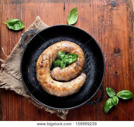 homemade sausages in a pan on a wooden background