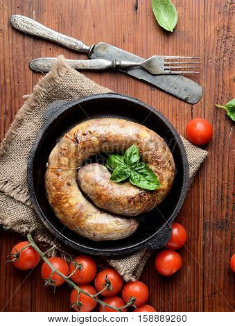homemade sausages in a pan on a wooden background