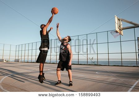 Full length portrait of two players with basketball at the playground
