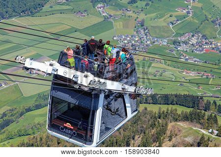 Mt. Stanserhorn, Switzerland - 7 May, 2016: people in a gondola of the Stanserhorn Cabrio cable car. Stanserhorn Cabrio is the the world's first double deck open top cable car, it carries 60 passengers per cabin with room for 30 on the open deck.