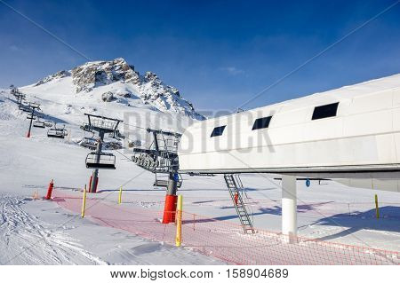 Ski lift station in mountains at winter. Alpine winter mountain landscape. French Alps covered with snow in sunny day. Val-d'Isere, Alps, France