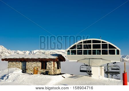 Ski lift station in mountains at winter. Alpine winter mountain landscape. French Alps covered with snow in sunny day. Val-d'Isere, Alps, France