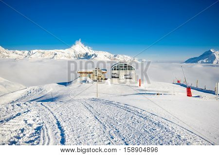 Ski lift station in mountains at winter. Alpine winter mountain landscape. French Alps covered with snow in sunny day. Val-d'Isere, Alps, France