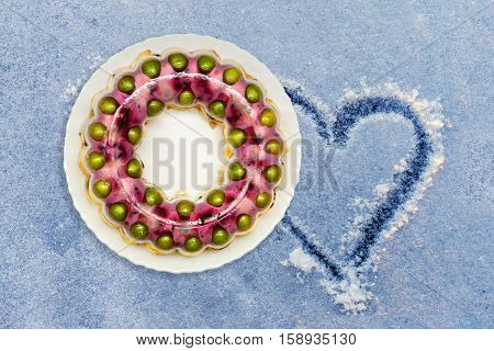 Jelly cake with milk and various fruits on a first snow shape of heart on snow.