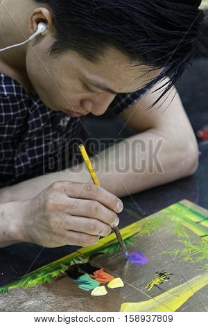 HANOI VIETNAM October 30 2016 : Unidentified artist paints in a workshop of lacquer of Hanoi. Lacquerware are objects decoratively covered with lacquer mostly from East Asian cultures.