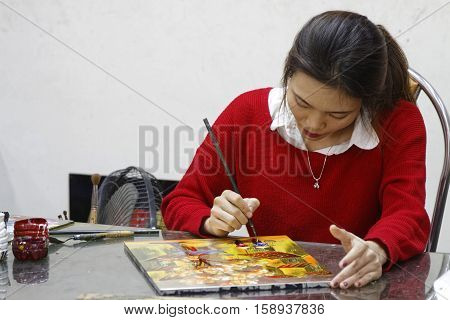 HANOI VIETNAM October 30 2016 : Unidentified artist paints in a workshop of lacquer of Hanoi. Lacquerware are objects decoratively covered with lacquer mostly from East Asian cultures.