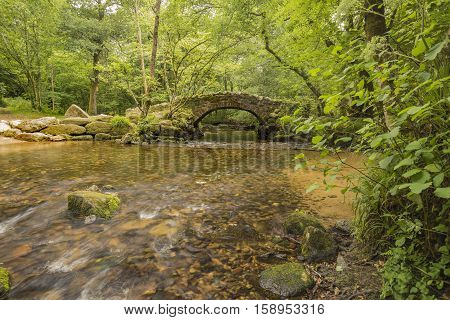 An image of an ancient packhorse bridge situated on the river Bovey Dartmoor Devon UK.