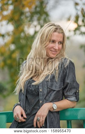 Attractive blonde young woman in a park with blurred background