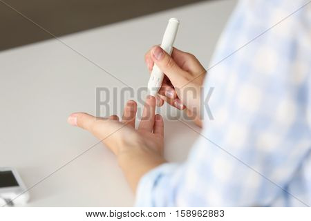 Woman using lancelet on finger