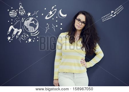 Young thinkful woman on blue gray background with universum icons. Confusion.