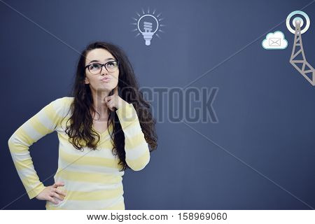 Young thinkful woman on blue gray background with finance graphs. Confusion. Predicament. Financial and business concept.