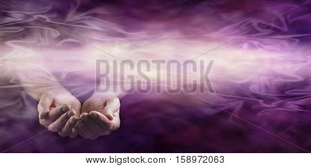 Offering healing energy banner  - pair of male hands gently cupped on left side with a stream of misty wafting energy across middle on a dark magenta purple background