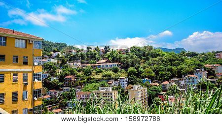 Blue sky with white clouds and the green area of Santa Teresa district with residential houses, Rio de Janeiro, Brazil