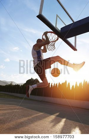 Young Man Jumping And Making A Fantastic Slam Dunk Playing Stree