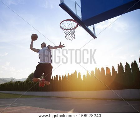 Young Man Jumping And Making A Fantastic Slam Dunk Playing Stree