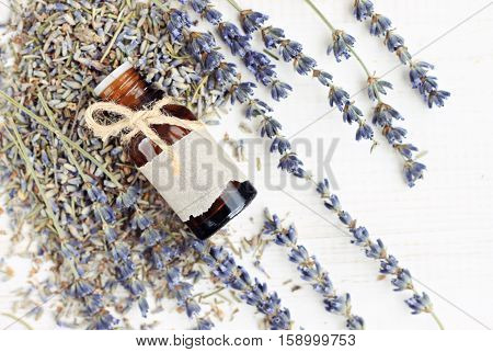 Lavender essential oil bottle decorated with twine bow and empty craft paper label, dried flower bunches, top view. Natural skincare beauty herb.