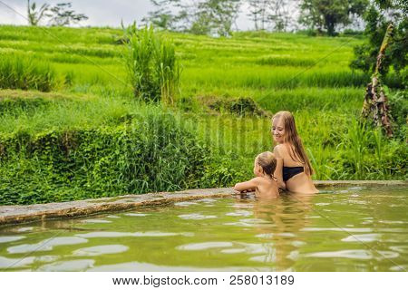 Mom And Son Travelers In Belulang Hot Springs In Bali On The Background Of Rice Terraces Traveling W