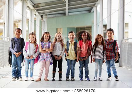 Elementary school kids stand in corridor looking at camera